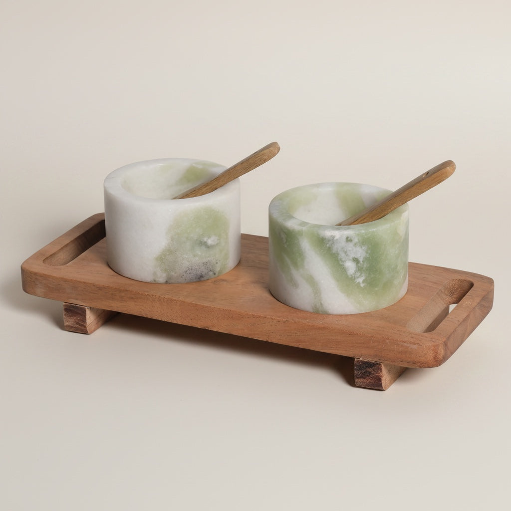 Himalayan green marble dual pinch pot set on raised acacia footed tray with wooden spoons — angled hero shot showing green-veined stone