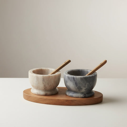 Two-tone marble pinch pot set — pale Selvada and deep grey Morchana pedestal cups on oval acacia tray with wooden spoons, hero shot